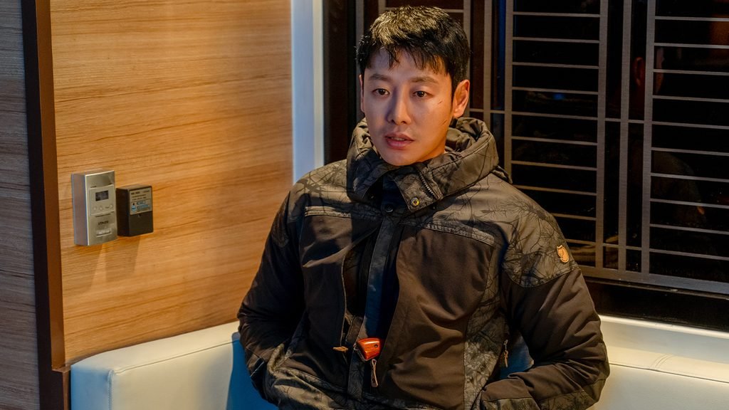 Kim Dong-wook sits in a dark padded jacket in The King of Pigs.