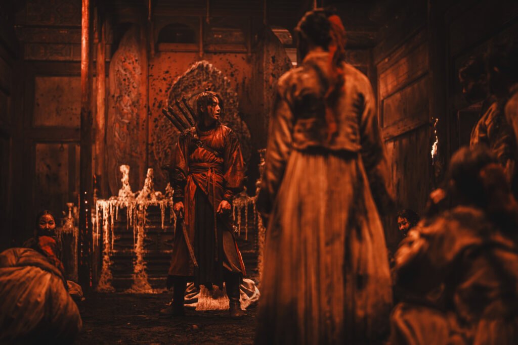 Figures inside a candlelit red chamber in The East Palace.